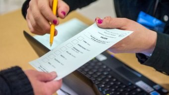 Electoral official pointing to ballot paper.