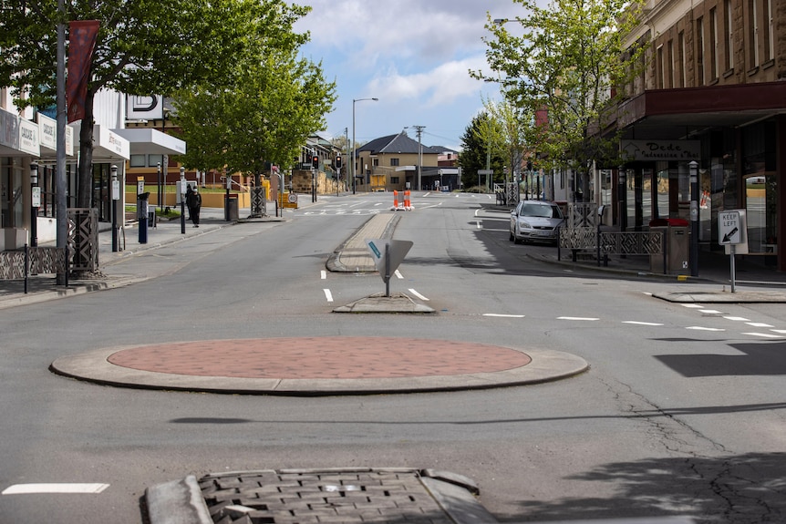 An empty city street with only one parked car visible.