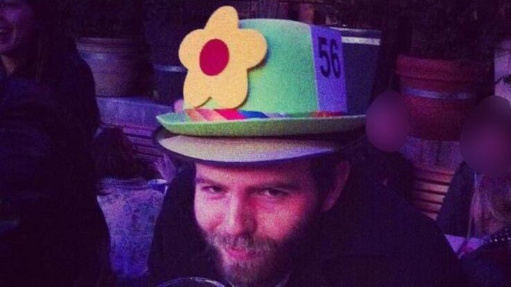 A man holding a beer wearing a flower hat