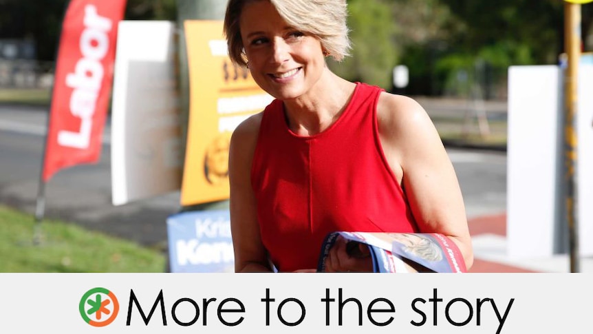 Wearing red, Ms Keneally stands outside a pooling both.