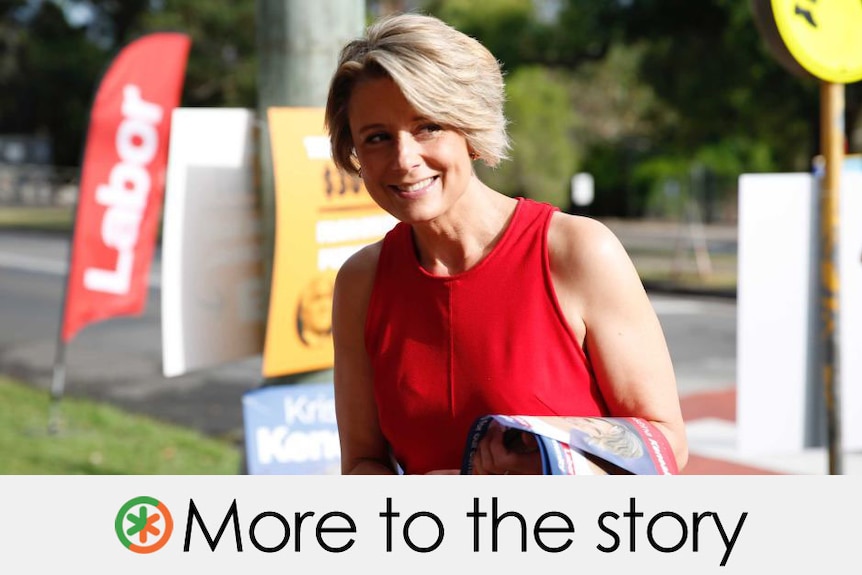 Wearing red, Ms Keneally stands outside a pooling both.