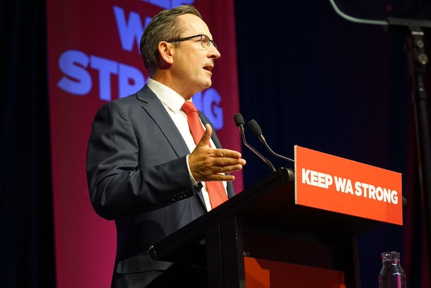 A close up photo of Mark McGowan wearing glasses at the podium of Labor's campaign launch.