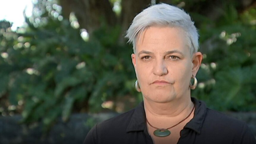 Woman with short white hair and big silver earrings