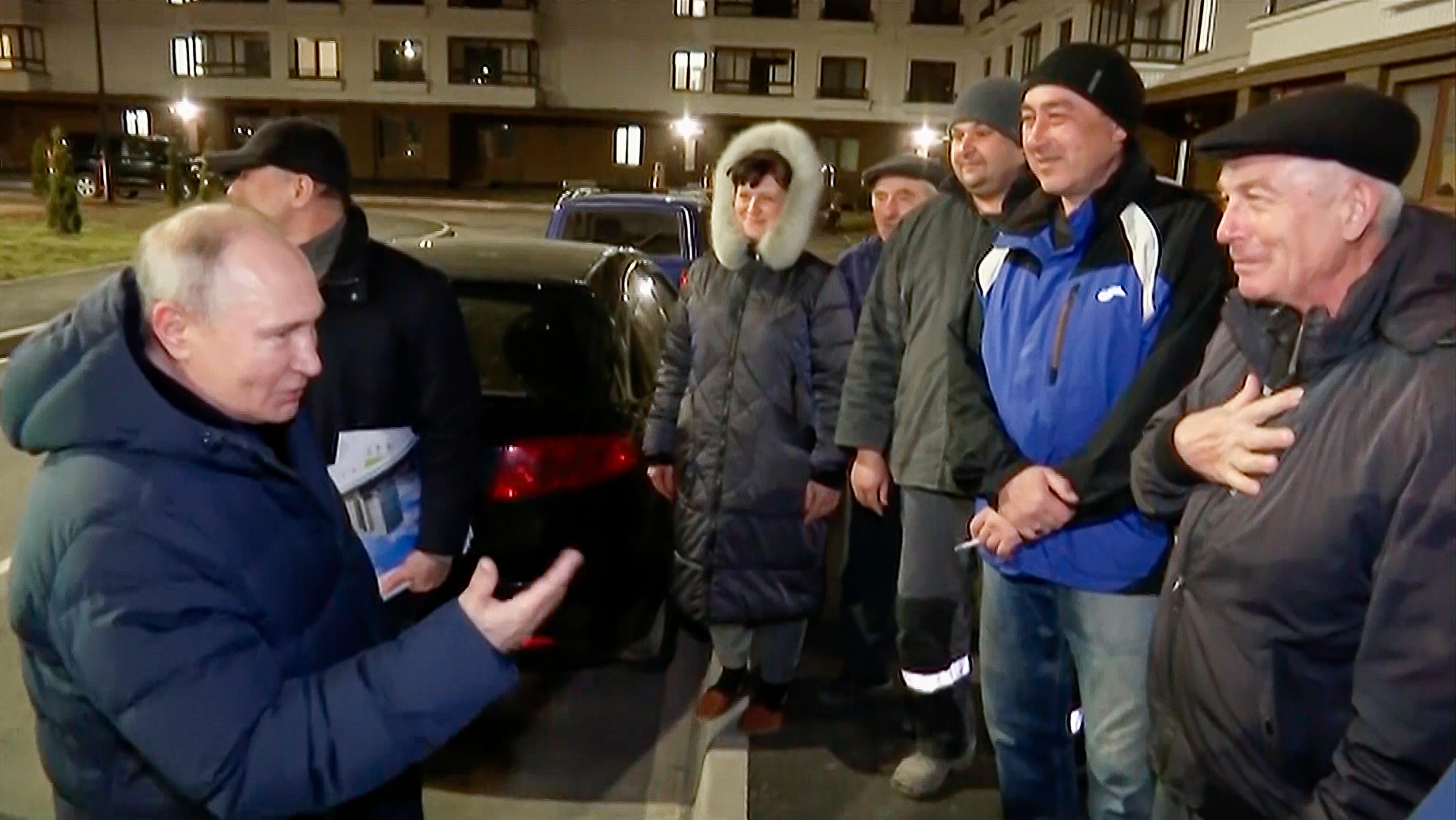 Vladimir Putin smiles as he talks to a group of residents at night on a city street