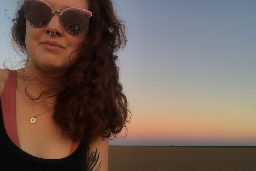 Malley wears sunglasses and takes a selfie with a stunning Kimberley sunset behind her.