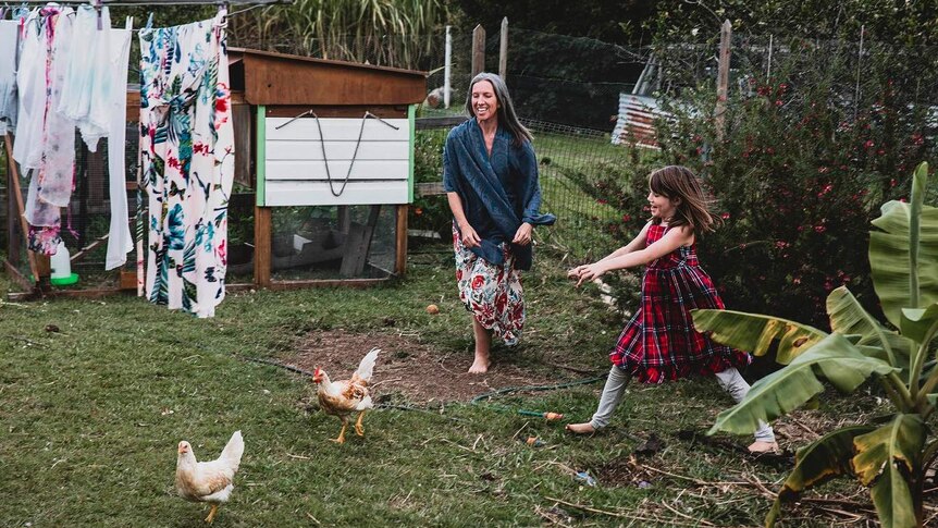 Ursula Wharton and her daughter chase after chickens in her backyard.