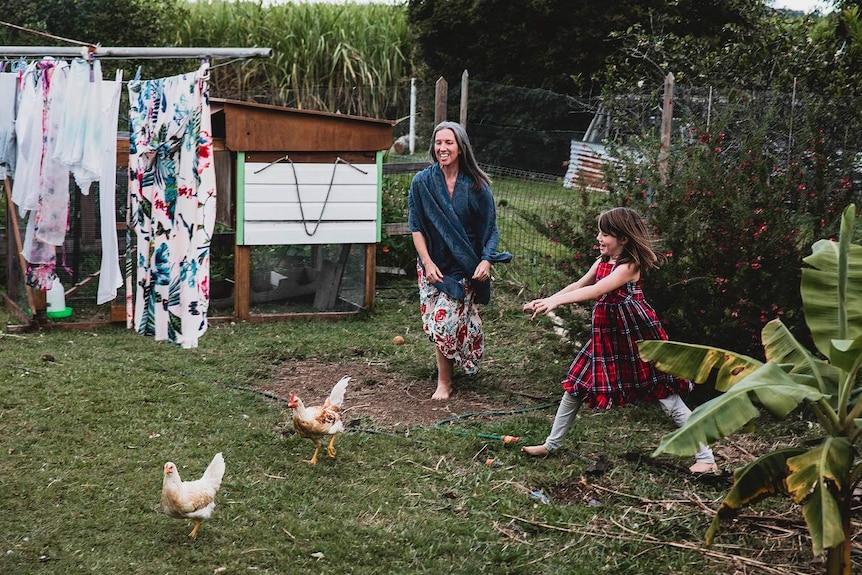 Ursula Wharton and her daughter chase after chickens in her backyard.