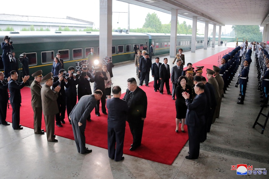 Kim Jong Un and dozens of officials on a train platform. 