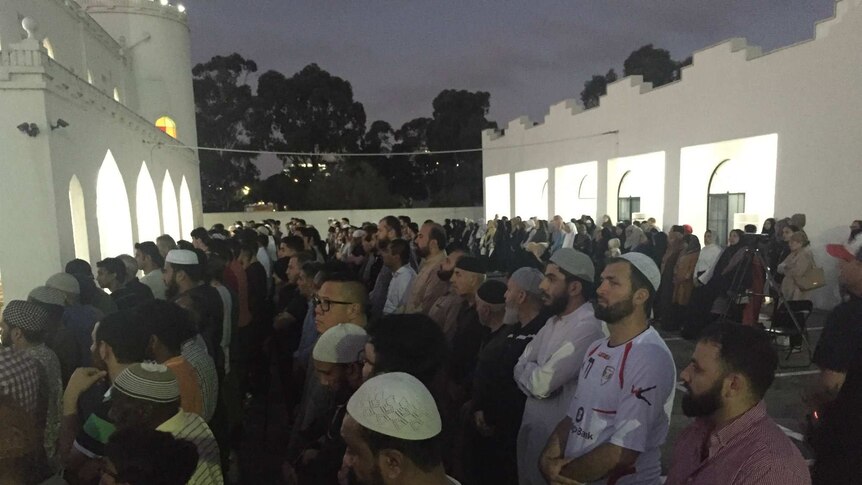 People stand in rows outside a mosque to pray as part of the prayer service for Aiia Maasarwe.