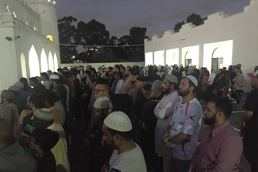 People stand in rows outside a mosque to pray as part of the prayer service for Aiia Maasarwe.
