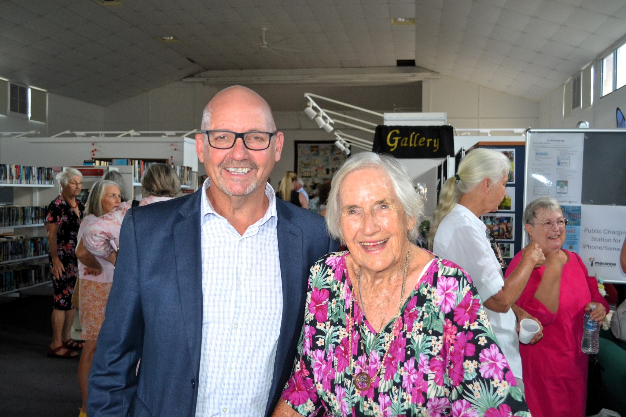 Marion Moore em sua exposição de arte com um homem de terno azul