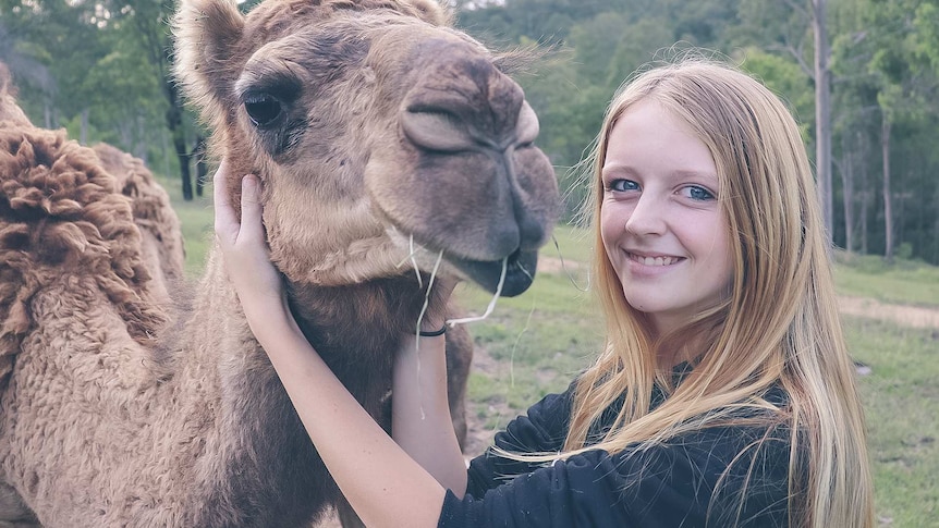 Girl hugging her pet camel.