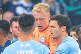 A bleeding Tom Glover of Melbourne City is escorted from the pitch during an A-League Men's soccer match.