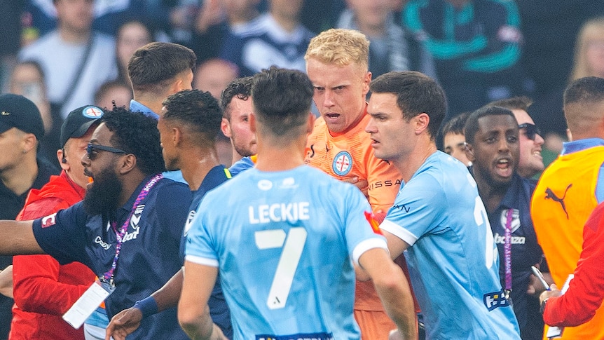 A bleeding Tom Glover of Melbourne City is escorted from the pitch during an A-League Men's soccer match.