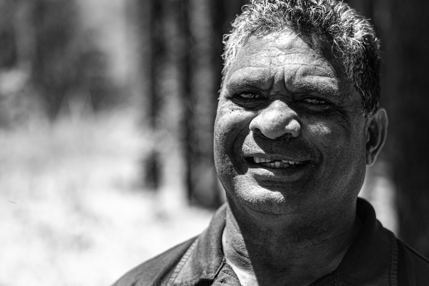 monochrome of man smiling in forest.