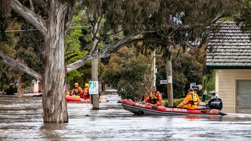 A rescue boat rides through streets that have become rivers.