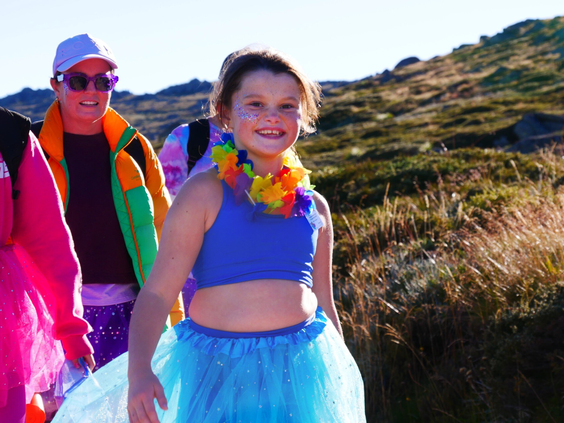 a girl smiles at the camera while walking in a blue tutu