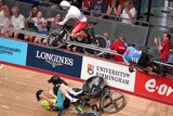 A male track cyclist lands in the crowd with his bike following a crash at the Commonwealth Games.