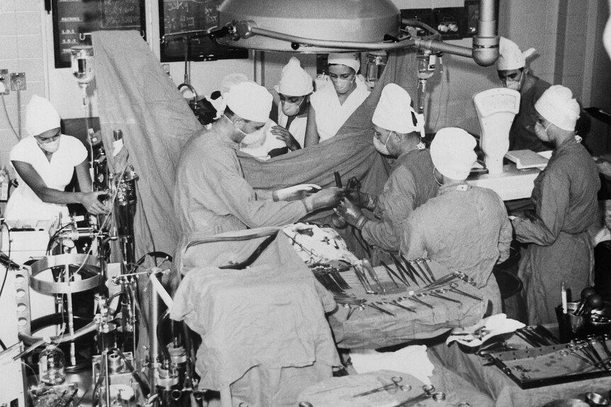 A black and white photo of a team of surgeons performing a heart transplant in 1967.