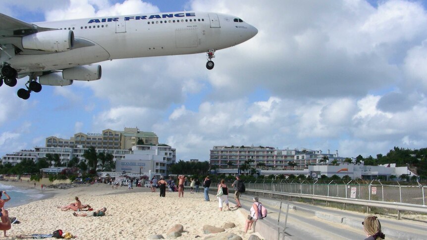 A plane comes in to land over the beach next to Princess Juliana Airport.