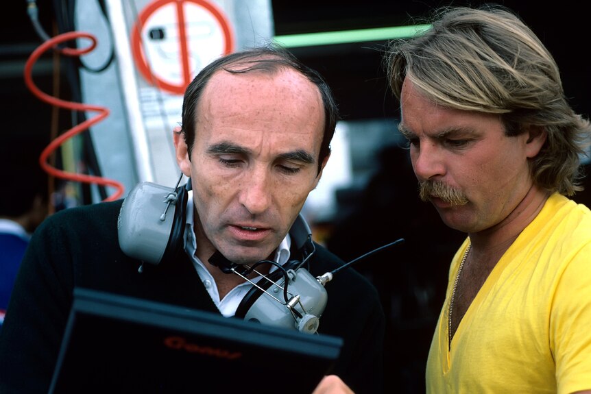 A Formula One team owner talks strategy with one of his drivers.