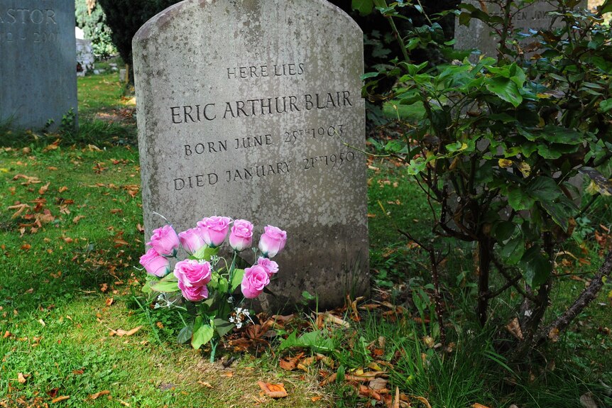 On an area of lush green grass, a tombstone with words 'Eric Arthur Blair' stands with pink roses near it.