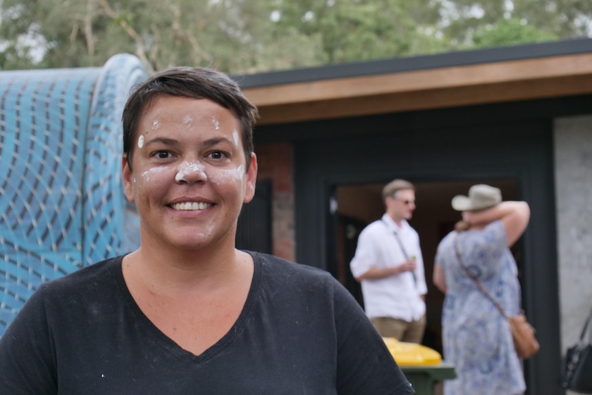 A smiling aboriginal woman with face paint.