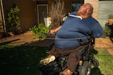 A man in a wheelchair outside a house.