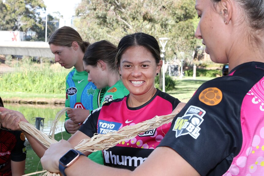 A woman smiles wearing a pink top