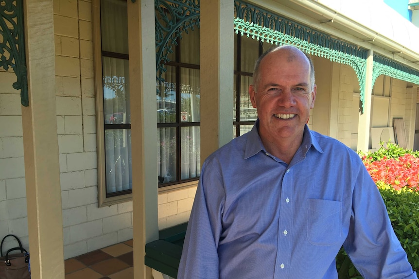 A man in a blue shirt stands outside a building.