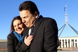 Jacqui Lambie hugs Nick Xenophon outside Parliament House in Canberra, the flagpole visible behind them.