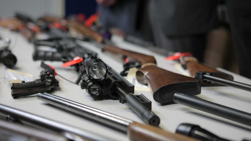 Several guns laid out on a table.