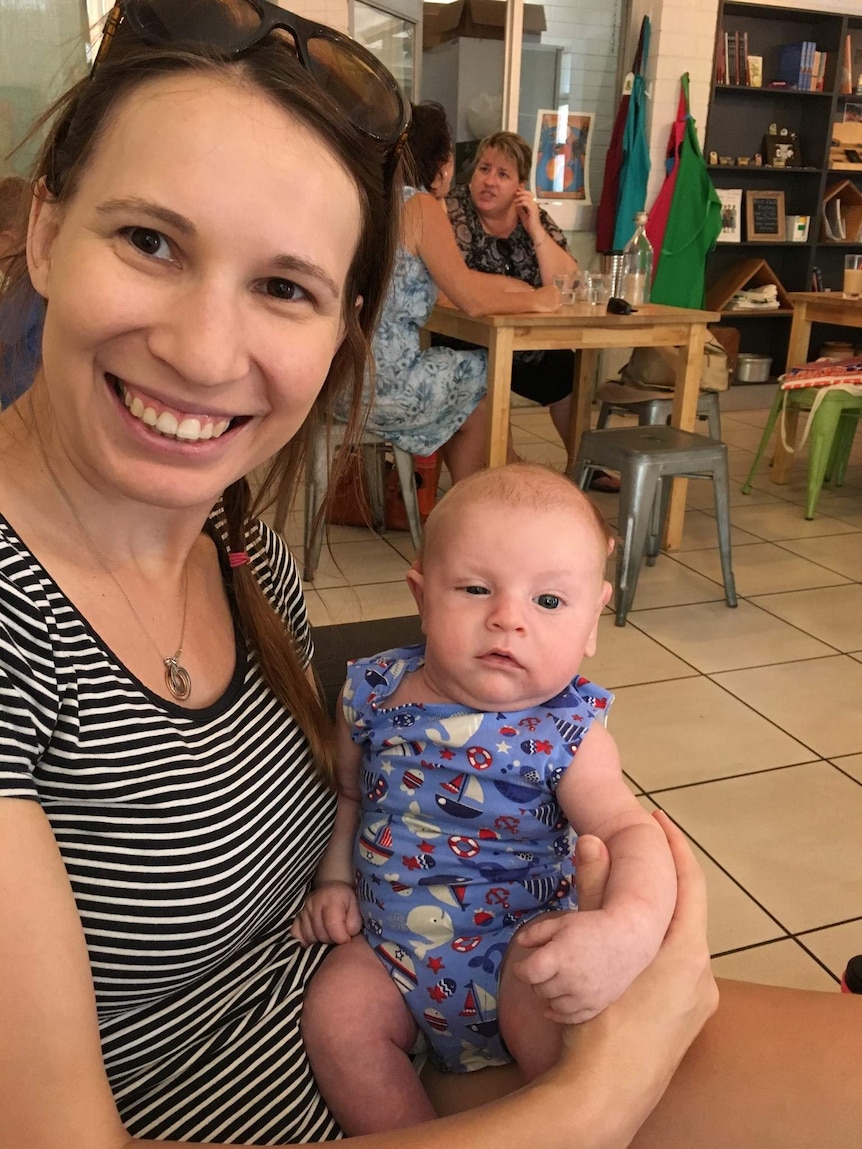 Pip Tallis holds baby Max in a cafe. Max has one eye half closed, and is only about four weeks.