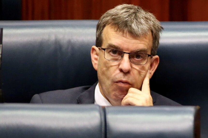 Dave Kelly looks at the camera while sitting on the leather seats of the lower house of Parliament.