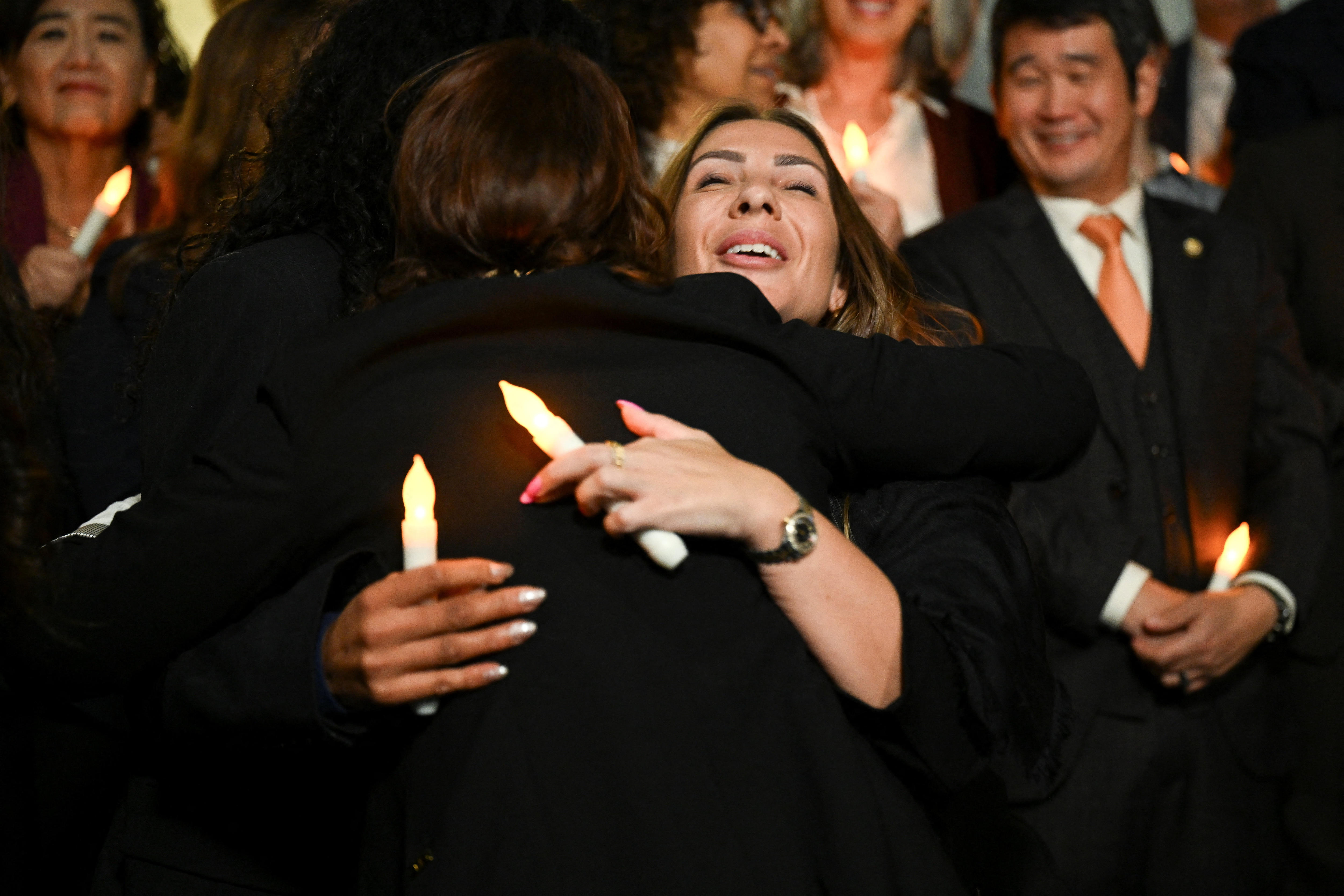 Two women hug in the middle of a crowd of people