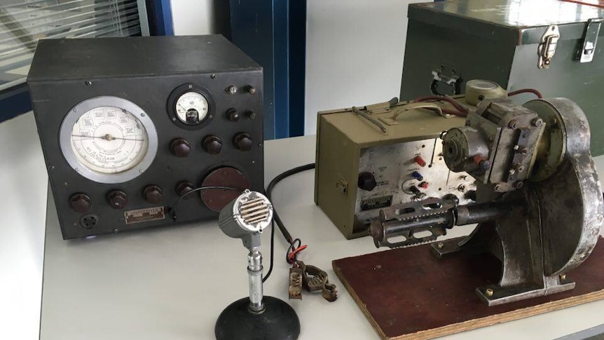 Old radio equipment, including a microphone, sitting on a table.