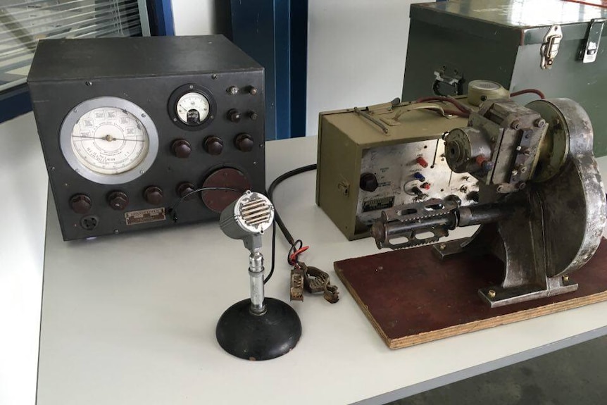 Old radio equipment, including a microphone, sitting on a table.