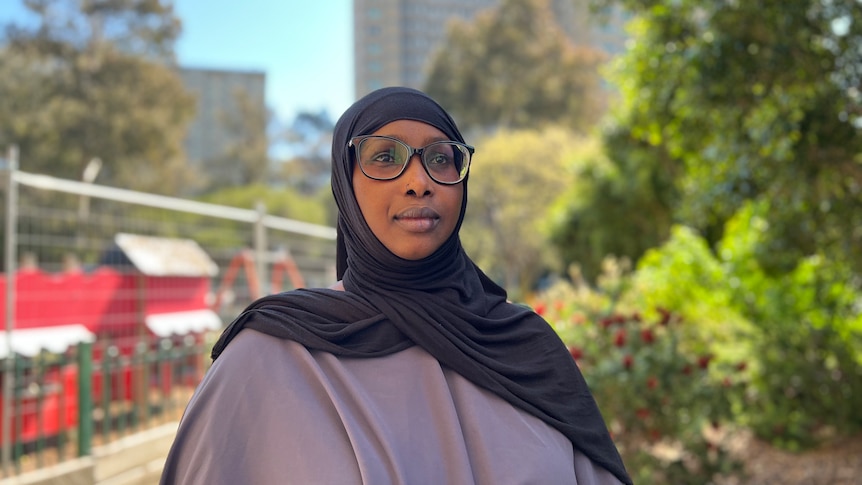 A woman wearing glasses and a hijab.