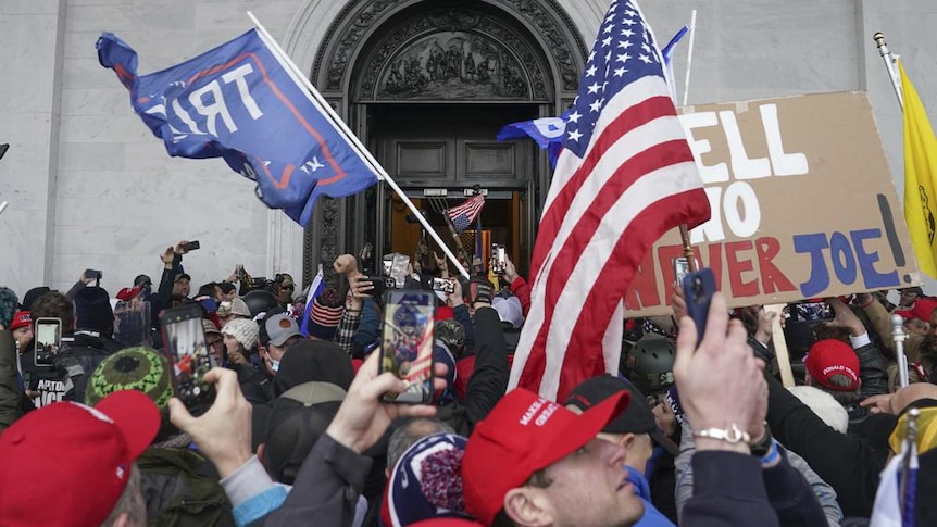 Rioters in the US hold up American flags outside the Capitol building 