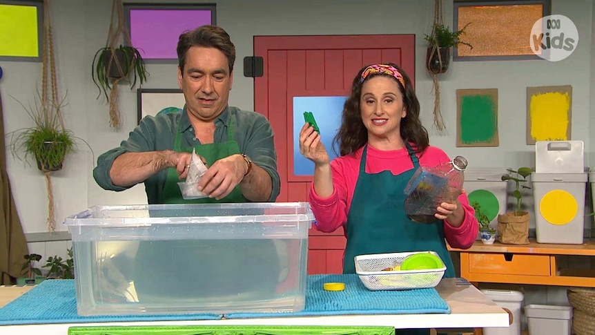 Alex and Emma on the Play School set with a large container of water and holding a plastic bottle and a plastic container