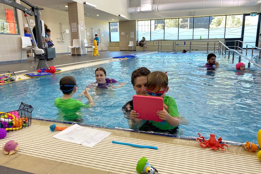Kids and teachers are in the pool, taking class in different ways.
