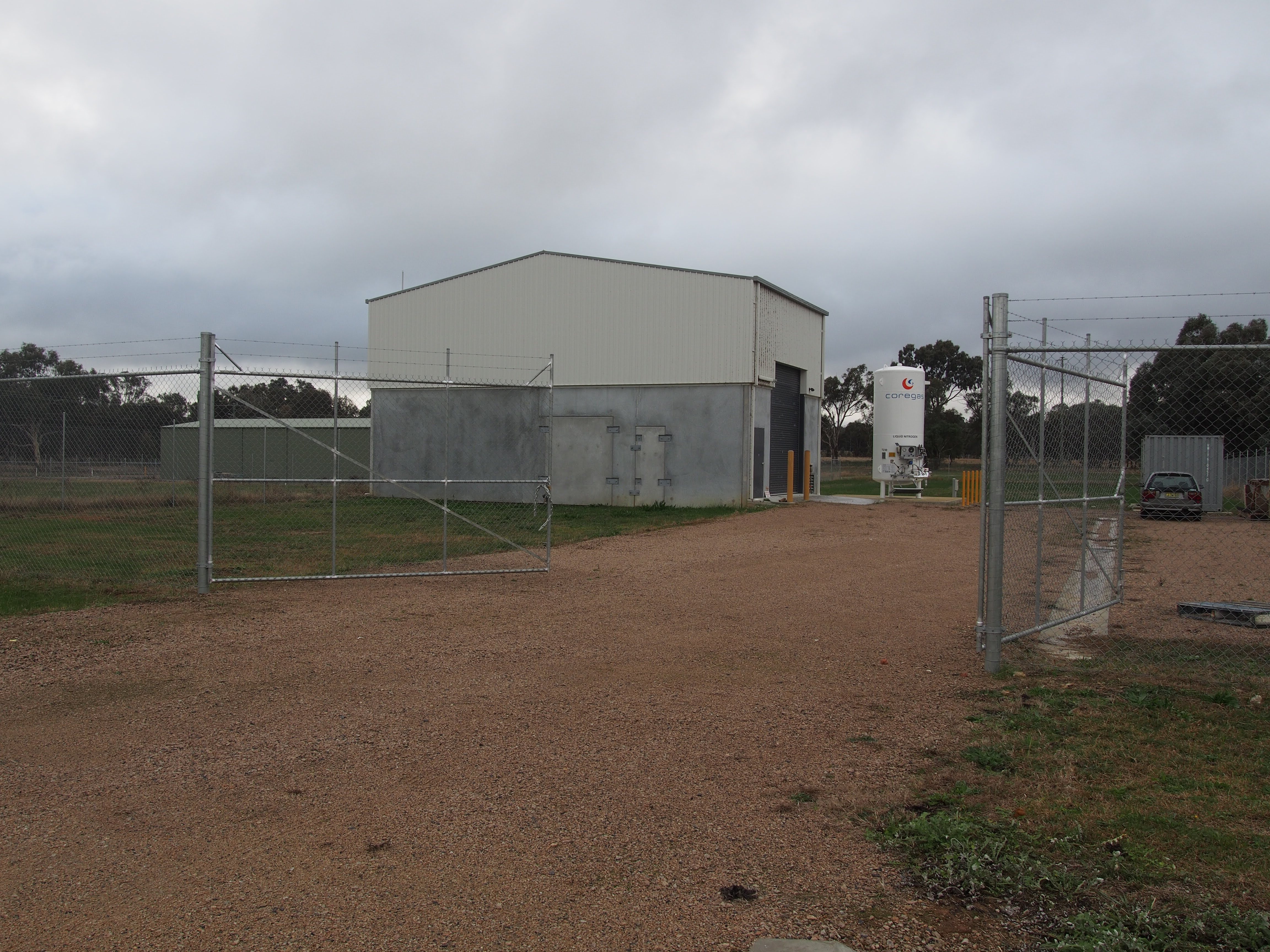 A shed in a paddock with a high fence around it 