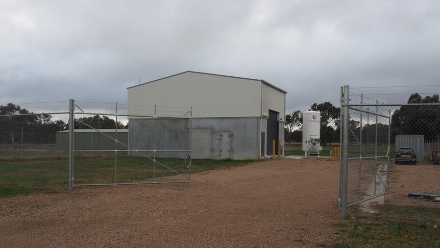 A shed in a paddock with a high fence around it 