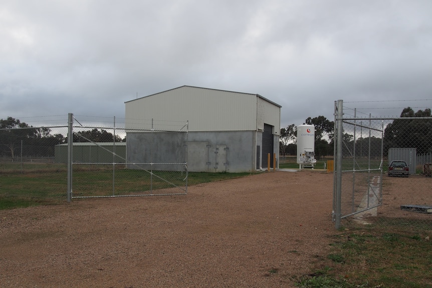 A shed in a paddock with a high fence around it 