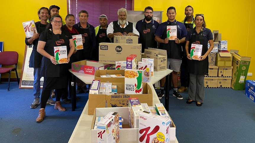 A group of people in aprons with boxes of food for hampers