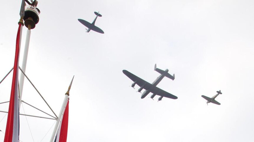 A Lancaster, Spitfire and Hurricane perform a fly past as the Royal Family look on