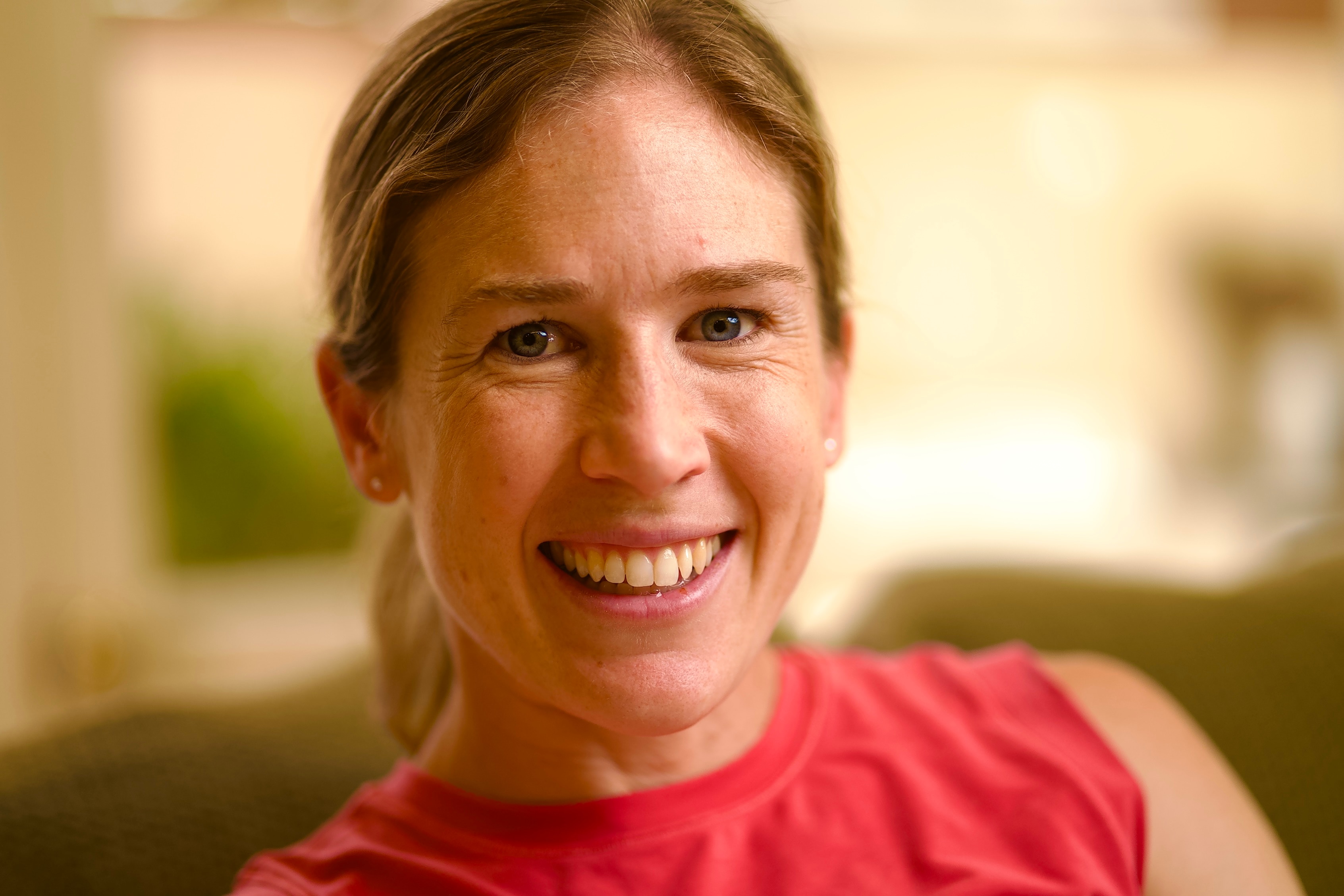 Um close de uma mulher sorridente em uma camiseta vermelha.