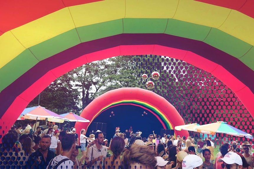 people under an inflatable brightly coloured rainbow