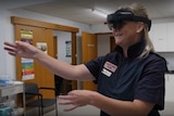 A nurse reaches her arms out while wearing a headset.