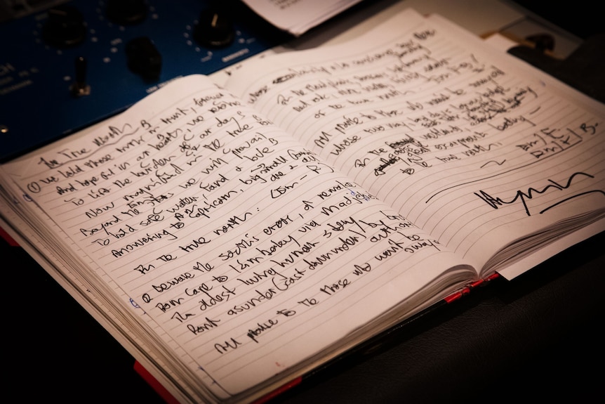 A notebook with handwritten lyrics open across two full pages of writing